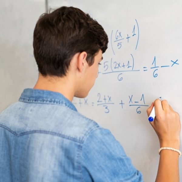boy answering math question on dry erase board